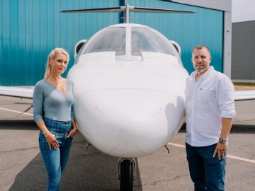 Die Geschäftsführerin von Silver Cloud Air und ein Mitarbeiter stehen gemeinsam vor dem Bug eines Businessjets.