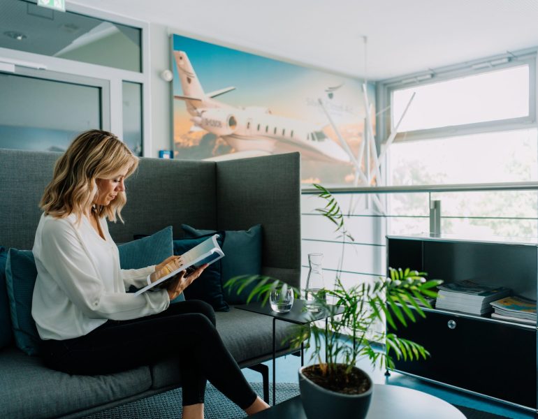 Mitarbeiterin von Silver Cloud Air sitzt in einer Lounge.