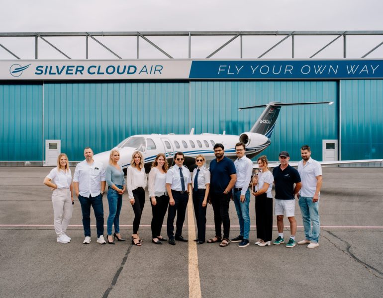 Gruppenfoto des Silver Cloud Air Teams mit Privatjet im Hintergrund.
